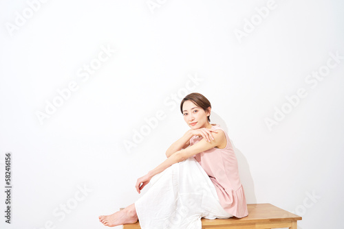 ベンチに座るミドルエイジ女性ののポートレート 白背景 コピースペースあり