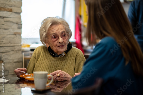 Nurse assisting senior woman with mealtime routine at a retirement home.