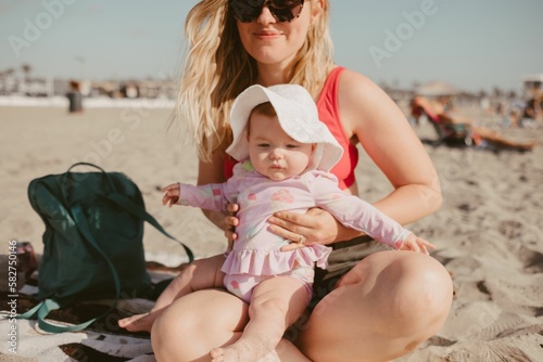 Closeup shot of a mother and a baby playing in sand on the beach