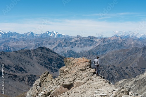 Scenic view of a man standing on top of the rocky mountain watching the mountain range around
