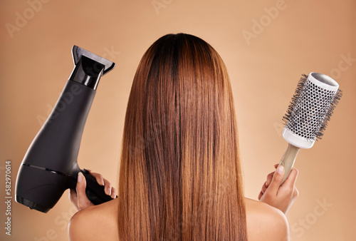 Hair, styling and brush with hairdryer and woman in studio for beauty, grooming and salon blowout. Cosmetics, glamour and treatment with back of model on brown background for products, style or clean