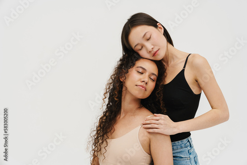 Two young girls posing isolated over white wall