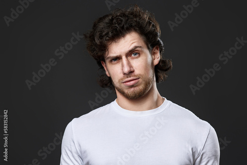 skeptic and nervous man in white t-shirt on dark gray background