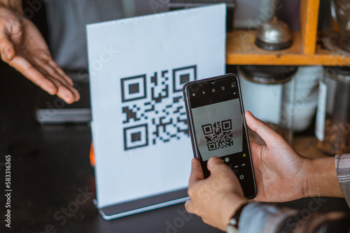 the hand of customer scanning the qr code using the phone
