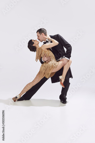 Portrait of stunning couple wearing vintage style clothes and dancing tango over white background
