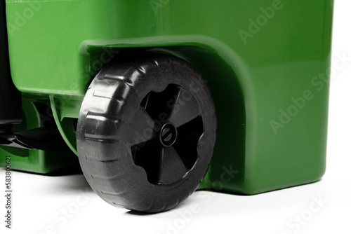 Green garbage wheelie bin close up on white
