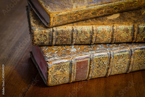 Pile of antique books with a leather cover and golden ornaments on a wooden table