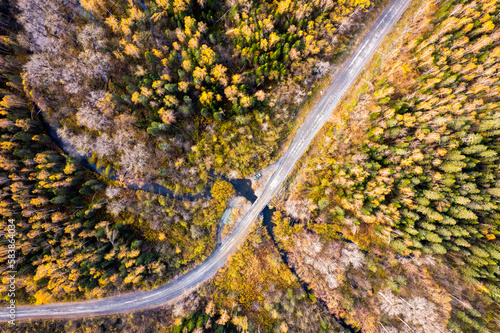 Drone view to a dirt road, river, car. Autumn forest.