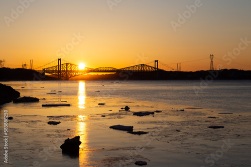The 1970 Pierre-Laporte and the 1904 Quebec bridges over the St. Lawrence river in silhouette during a beautiful golden early spring sunrise, Cap-Rouge area, Quebec City, Quebec, Canada