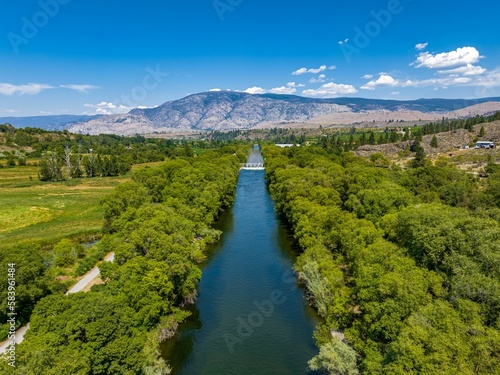 View of channel near vineyards in Oliver, British Columbia, Canada with valley and mountain cliffs