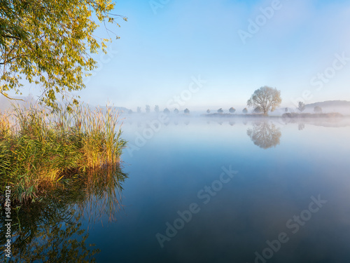 Lake under blue sky in autumn with morning fog