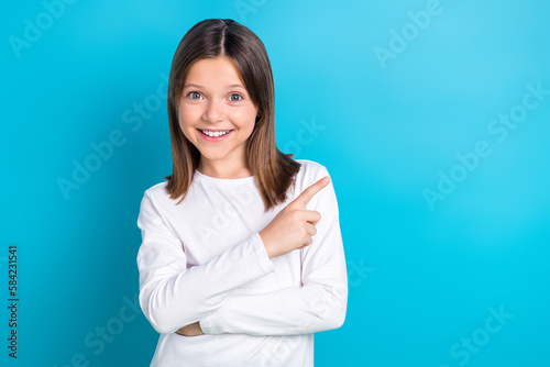 Photo portrait of charming schoolgirl point empty space beaming smile shopping wear trendy white clothes isolated on blue color background