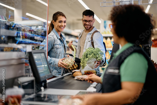 Young happy couple buying groceries in supermarket.