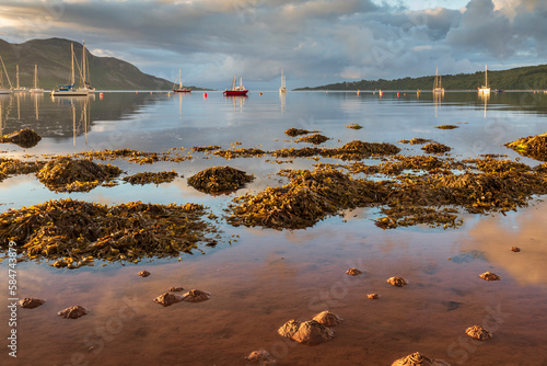 Boats moored in the sheltered bay of Lamlash, with the shores of Holy Island beyond, on the Isle of Arran in Scotland.