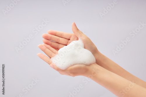 White cleanser foam texture placed on female hand model on a white background. Cleanser product advertising. Skincare concept