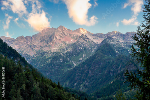 Paesaggio alpino nel Parco Naturale dell'Alta Valsesia in estate. Tramonto in montagna con l'ultimo raggio di luce sulle cime. Cielo e nuvole. Alpi italiane. Alagna Valsesia. Piemonte. Alpi Italia