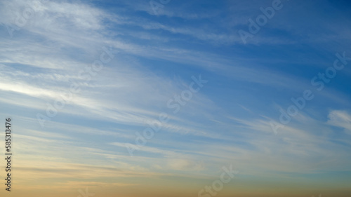 Cirrus clouds float in the blue evening sky