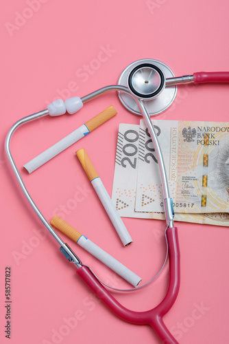 Palenie papierosów a zdrowie - papierosy obok pieniędzy i medycznego stetoskopu 