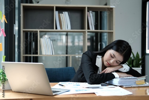 Tired businesswoman sleeping with document on the desk at office. Overwork, working overtime and stress at work concept.