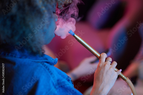 Young woman smoking hookah when hanging out with friends