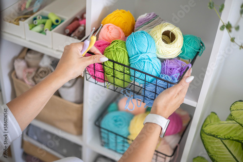 Female hands placing basket with colored ball of yarn art crochet knitting ribbon cotton wool thread