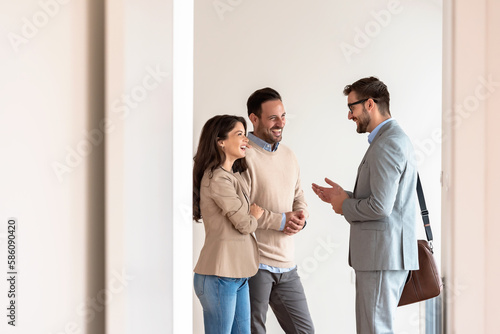 Young married couple talking with a real-estate agent visiting an apartment for sale or for rent. Future parents buying an apartment. Real estate concept. A new beginning