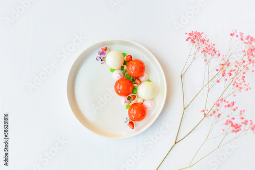Bright dessert on a white plate with strawberries and mousse