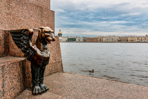 Sculpture of Griffin - bronze winged lions 1834 on the University Embankment of the Neva river with the background view of Isaac Cathedral, Saint-Petersburg, Russia