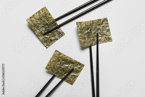 Chopsticks with nori sheets on white background