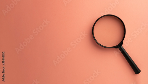 Photo of magnifying glass on right side over pink pastel background with copyspace for put your text or logo.,Flat lay top view mock-up item concept.