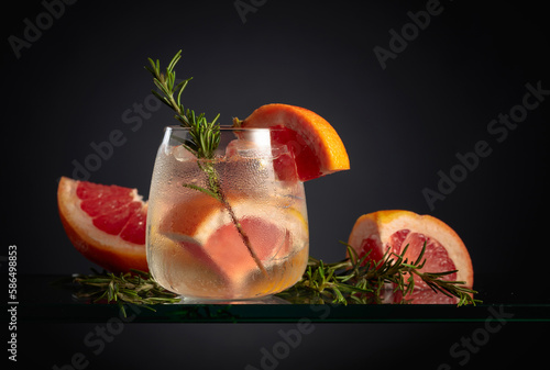 Cocktail gin tonic with ice, grapefruit, and rosemary.