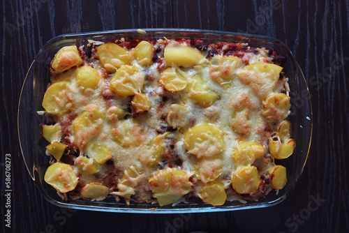 Potato casserole with kidney beans. Topped with cheese in a casserole dish. Top view