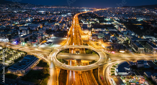 Aerial view of a illuminated multilevel junction ring road as seen in Attiki Odos toll road motorway interchange with Kifisias Avenue in Athens, Greece, during night time