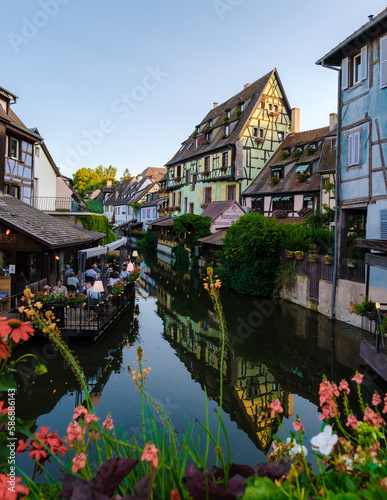 Colmar France July 2021, Beautiful view of the colorful romantic city of Colmar in the evening with people dinner at the restaurant alongside the canal
