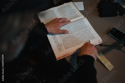 Eine Person blättert durch ein religiöses Buch mit hebräischen Schriftzeichen und nutzt einen Zeiger für die Lesung