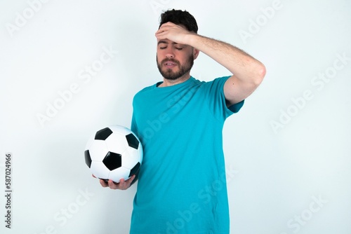 Young man holding a ball over white background Touching forehead for illness and fever, flu and cold, virus sick.