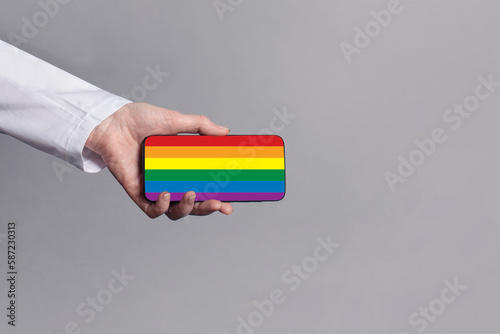 Doctor hand in medical uniform showing mobile phone with LGBT flag on it. Support, medication, stop discrimination concept