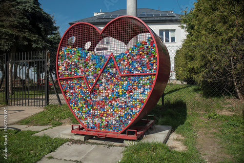 Pojemnik w kształcie serca do zbierania plastikowych nakrętek, ustawiony w miejscu publicznym