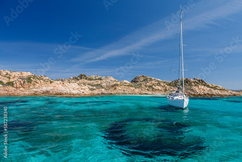 foto panoramica di una costa con il mare cristallino e una barca a vela