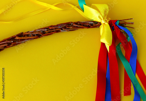 Easter braided whip, traditional symbol of Czech and Slovak Easter. Close up of Easter handmade whip with colorful ribbons on yellow background. Top view with copy space