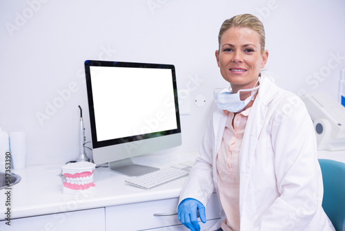 Dentist working while sitting by computer at medical clinic