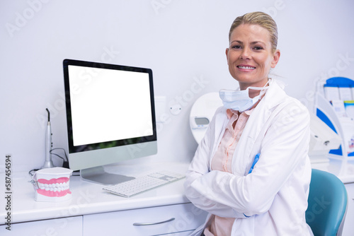 Portrait of smiling dentist working while sitting by computer