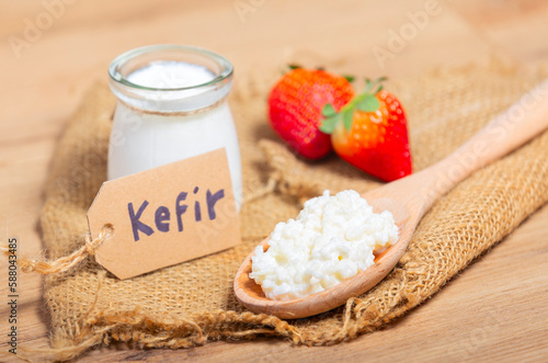 Kefir grains in wooden spoon in front of cups of Kefir Yogurt Parfaits. Kefir is one of the best health foods available providing powerful probiotics.