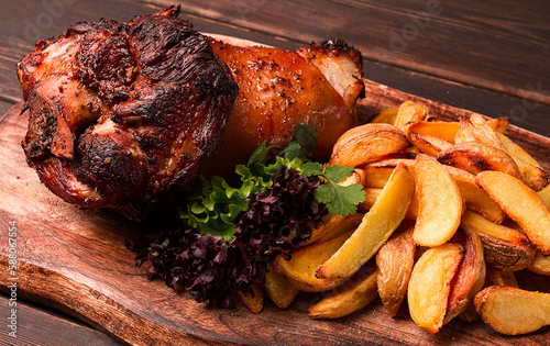 Pork knuckle, in soy-honey sauce, with fried potatoes, on a wooden chopping board, homemade, no people,