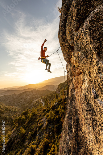 man climbing at sunset in the mountains with the forest in the background, copy space, business, security, trust