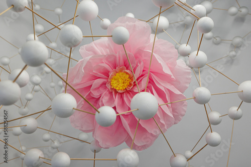 Artistic Depiction of a Pink Flower in Crepe Paper surrounded by a Structure of White Spheres connected Together