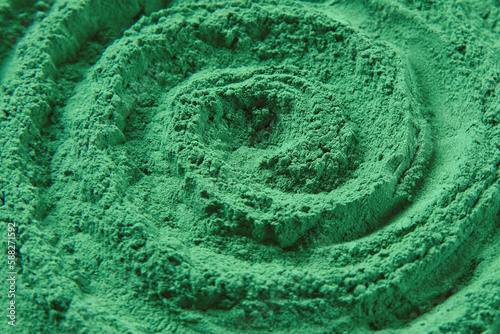 Chlorella or spirulina algae green powder is spinning, rotation. Dietary supplement to improve health. Seaweed superfood. Healthy food background. Vitamins and minerals to diet. Detox. Close up photo