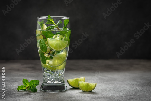 Mojito cocktail. Summer refreshing mojito drink with ice, lime and fresh mint on a dark background. Side view, selective focus, copy space.