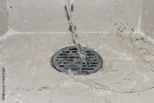 A water of stream is pouring on the shower drain grate