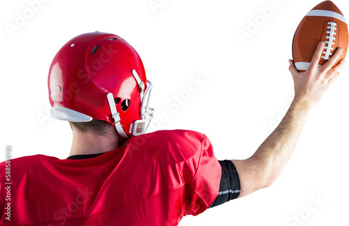 Rear view of american football player holding up football